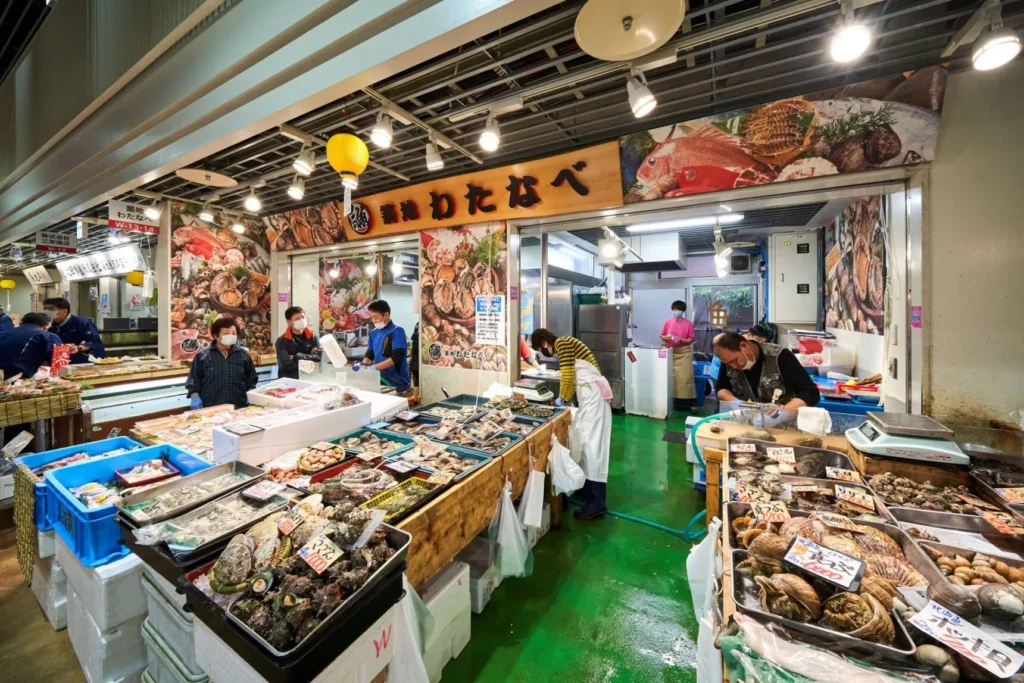 Fresh sashimi-grade fish display at Tokyo Fish Market with expert staff preparing orders